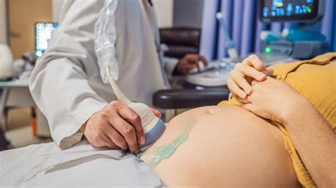 Lekári udržujúci životné funkcie tehotnej ženy pomocou prístrojov