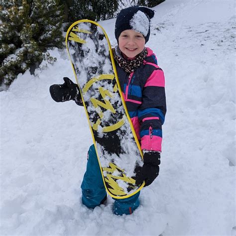 Detský snowboard s meracou páskou postavený vedľa dieťaťa