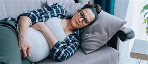 žena relaxuje na pohovke s bruškom, symbol pokoja v tehotenstve