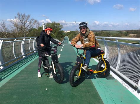 Fotografia rodiny jazdiacej na elektrobicykloch s detským vozíkom.