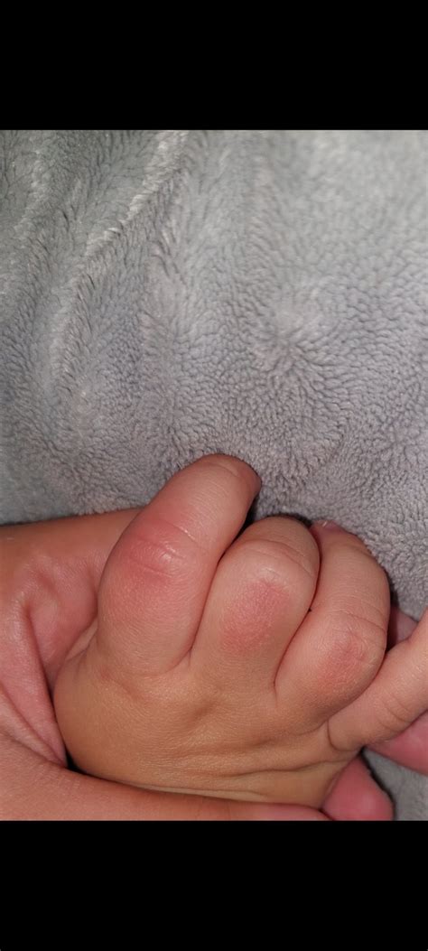 Dieťa drží prst dospelého v úchopovom reflexe